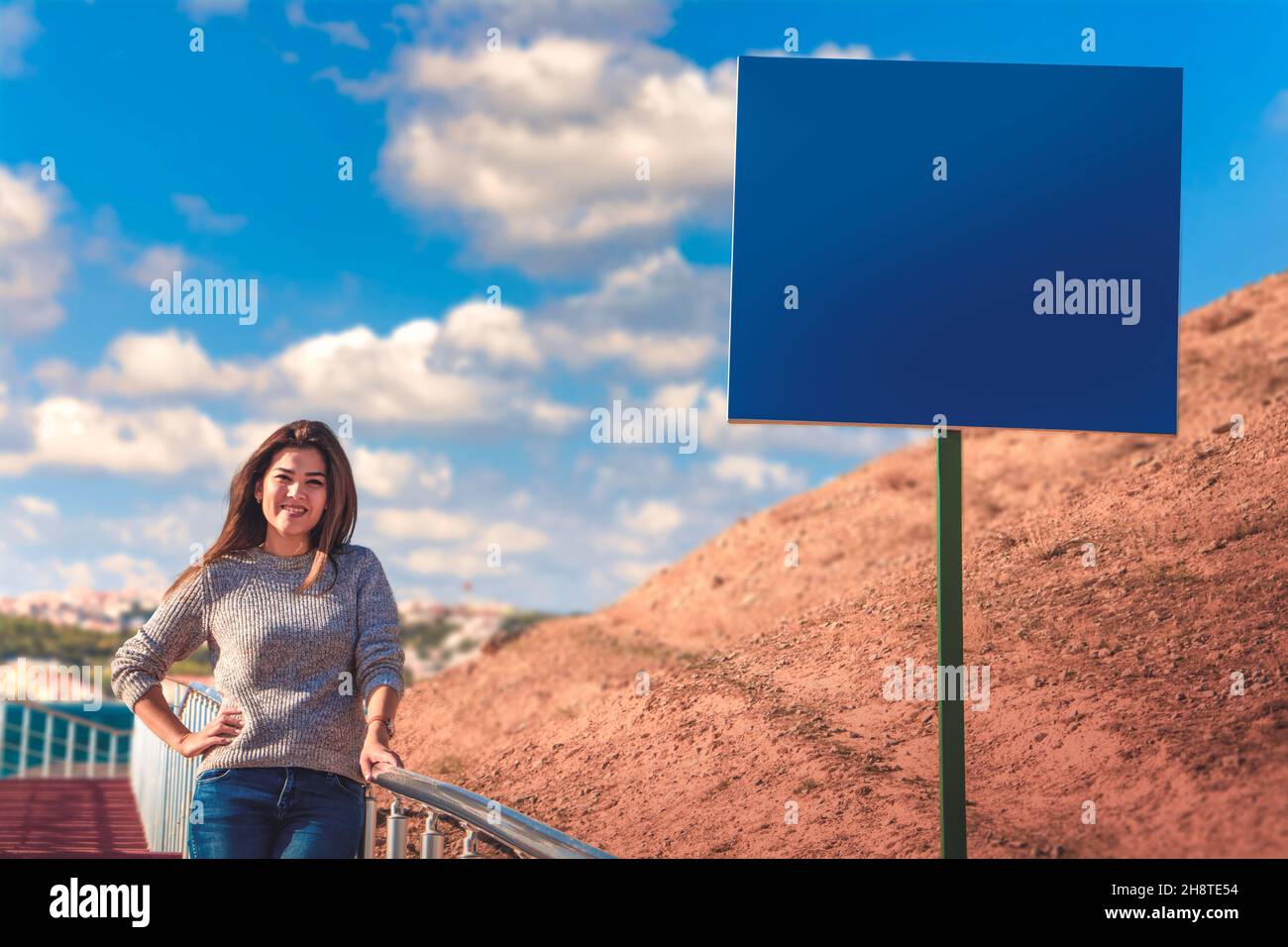 an asian girl on stairs with a cityscape in the background and a mockup sign in the foreground Stock Photo