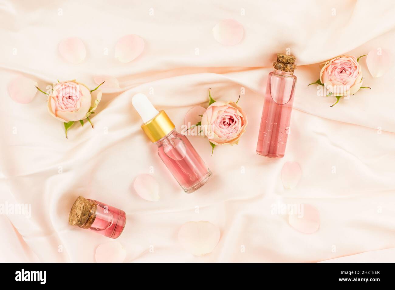 Nature cosmetics in glass bottles on a textile pastel background. rose ...