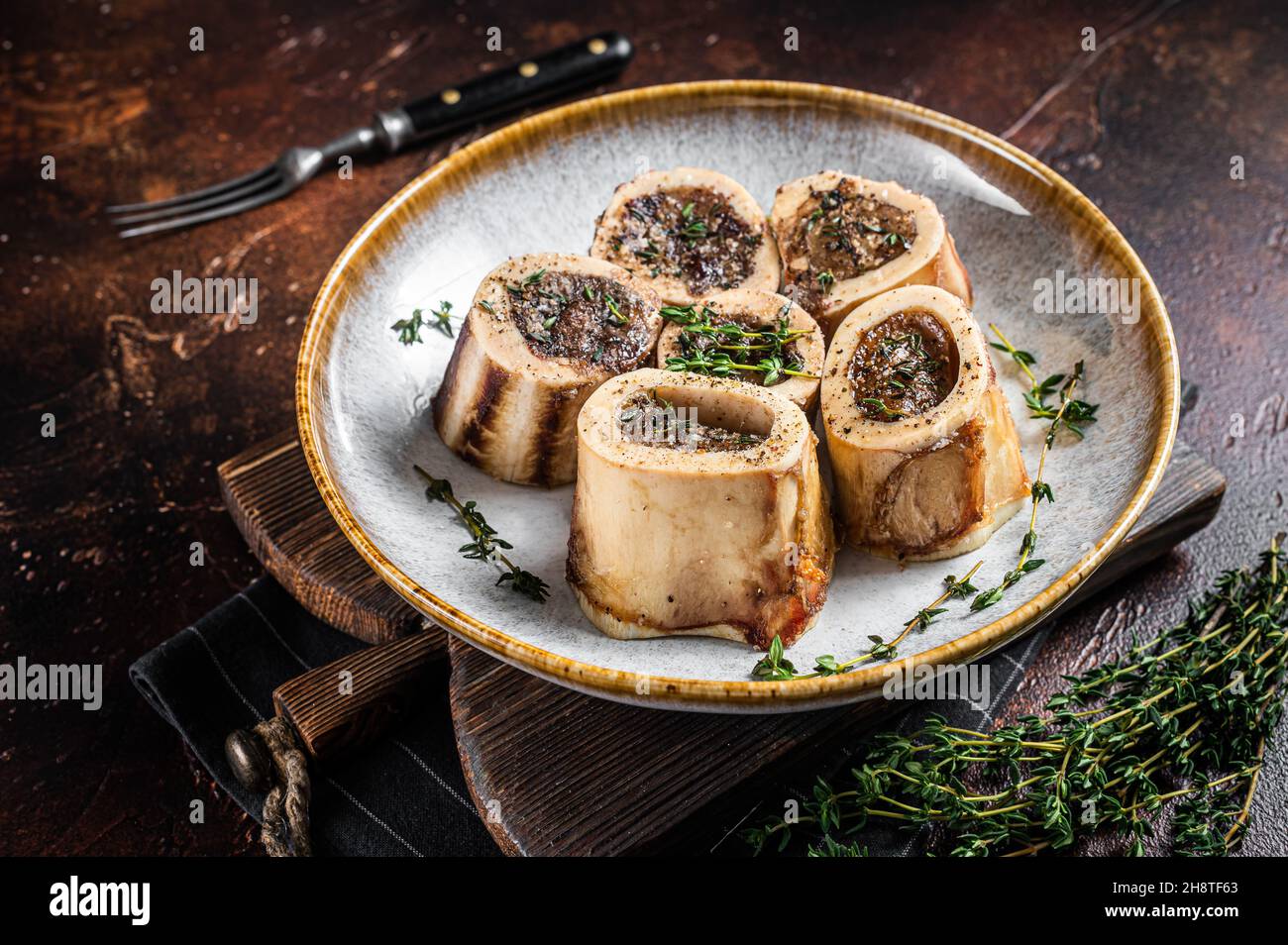Baked marrow veal beef bones in plate with thyme and herbs. Dark