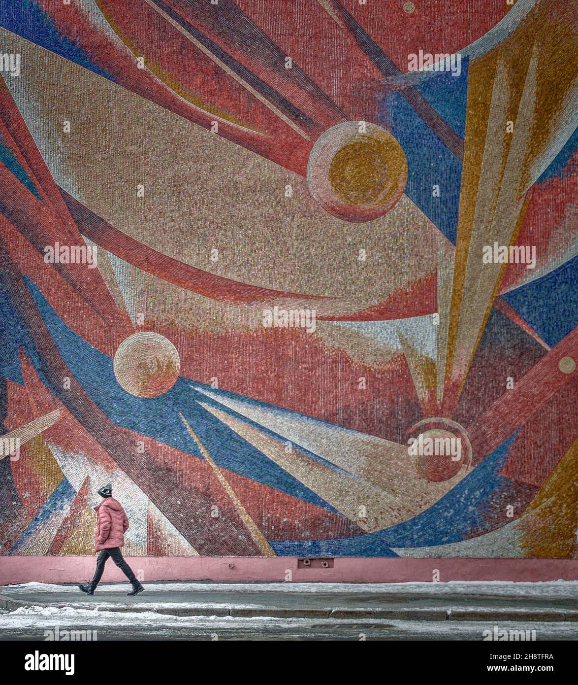 23rd of February 2019, Russia, Tomsk, teenager walks by the art panel with cosmic theme on the wall Stock Photo