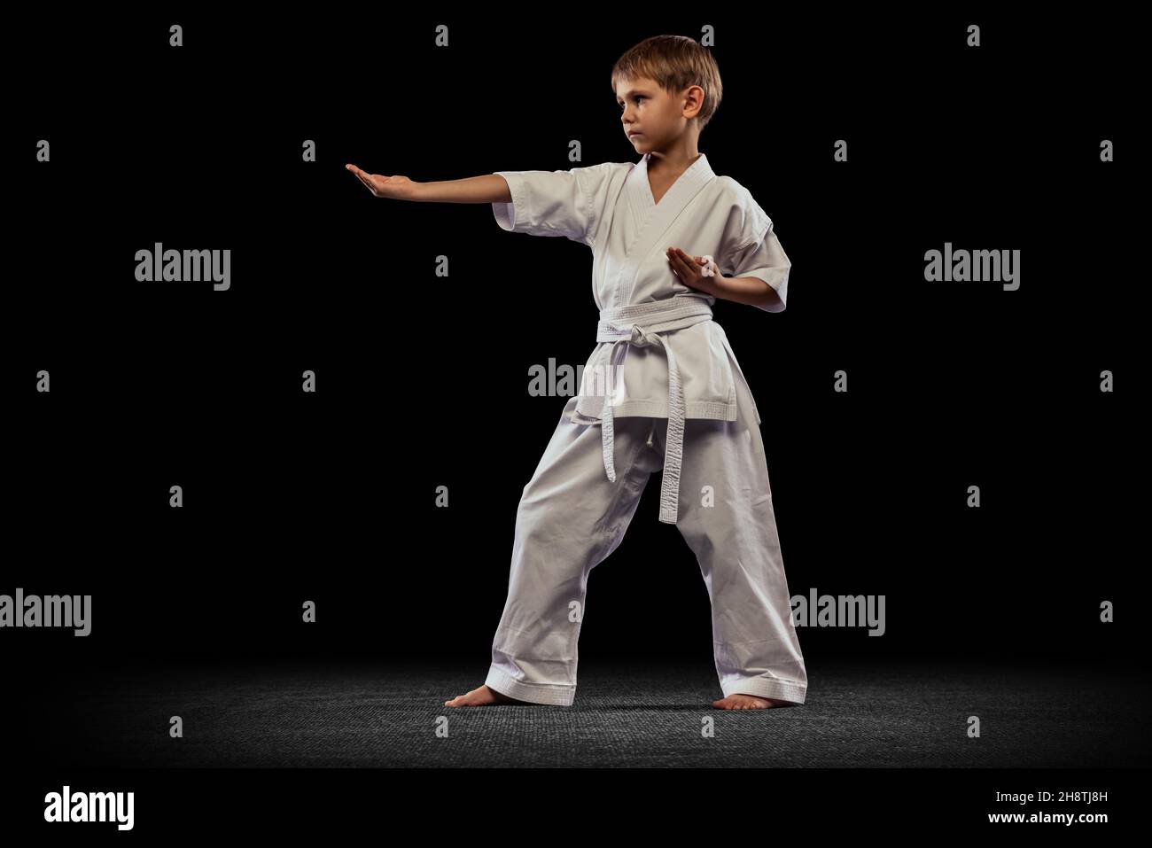 Portrait of little boy, sportsman training martial art isolated over black background Stock Photo