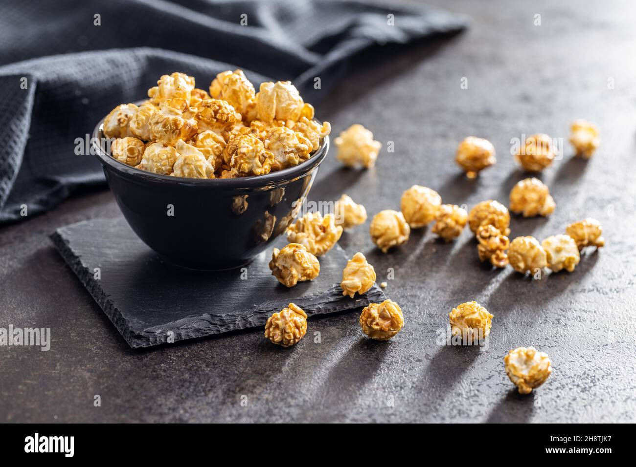 Sweet caramel popcorn in bowl on black table. Stock Photo