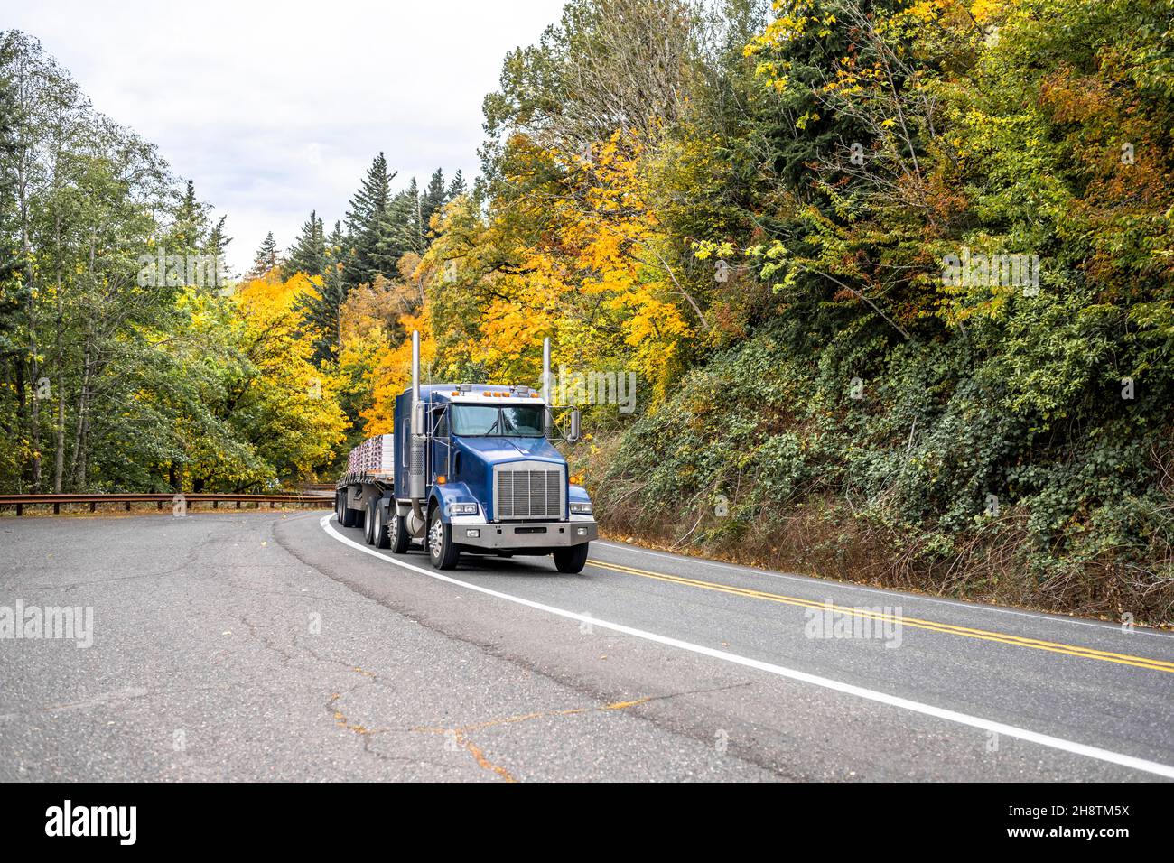 Industrial big rig blue semi truck tractor transporting stacked ...