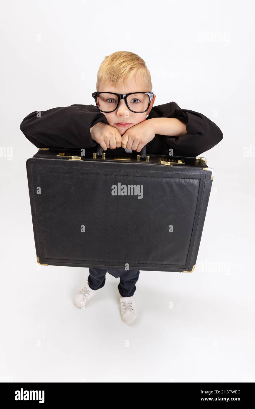 Portrait of a young boy wearing his dad's work clothes and holding a  briefcase - SuperStock