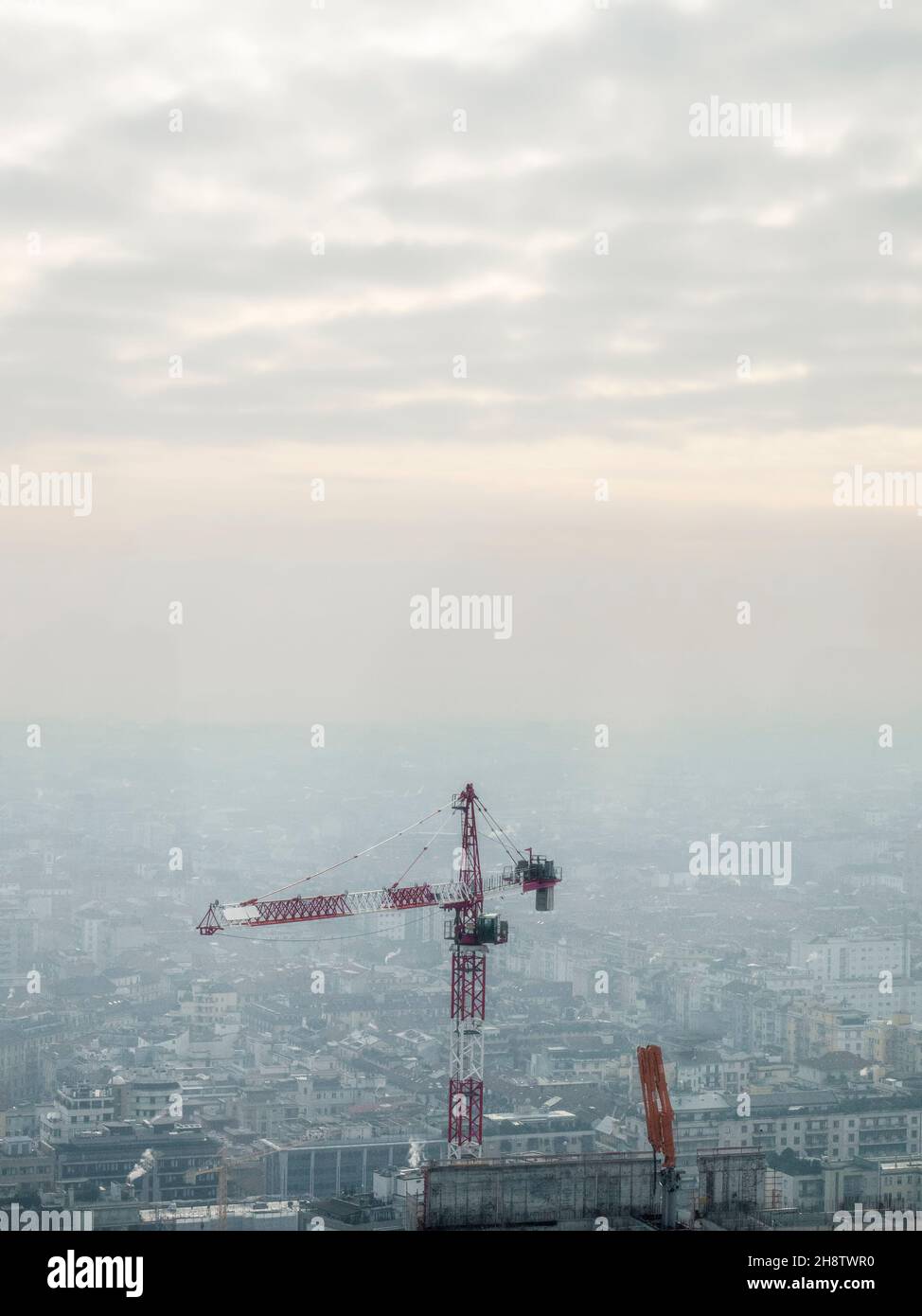 A large construction crane with the city of Milan in the background Stock Photo