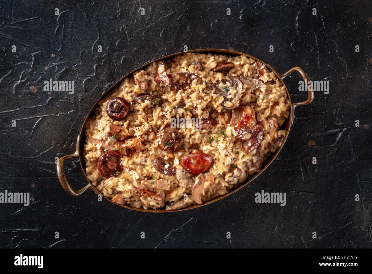 Risotto ai funghi, mushroom risotto, rustic rice with mushrooms, top shot on a black background Stock Photo