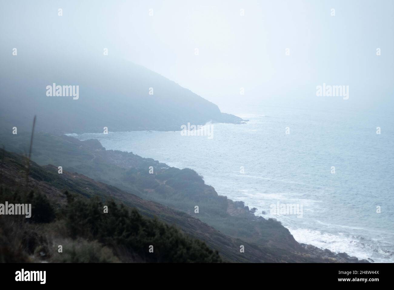 Mesmerizing view of hills on the coast of the sea on a foggy day Stock ...