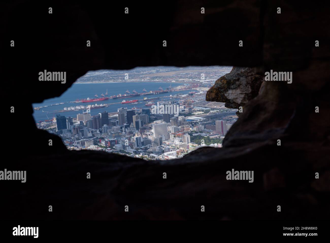 A perspective of the South African city of Cape Town, framed by a cave entrance on Signal Hill and one of the city's landmarks Stock Photo