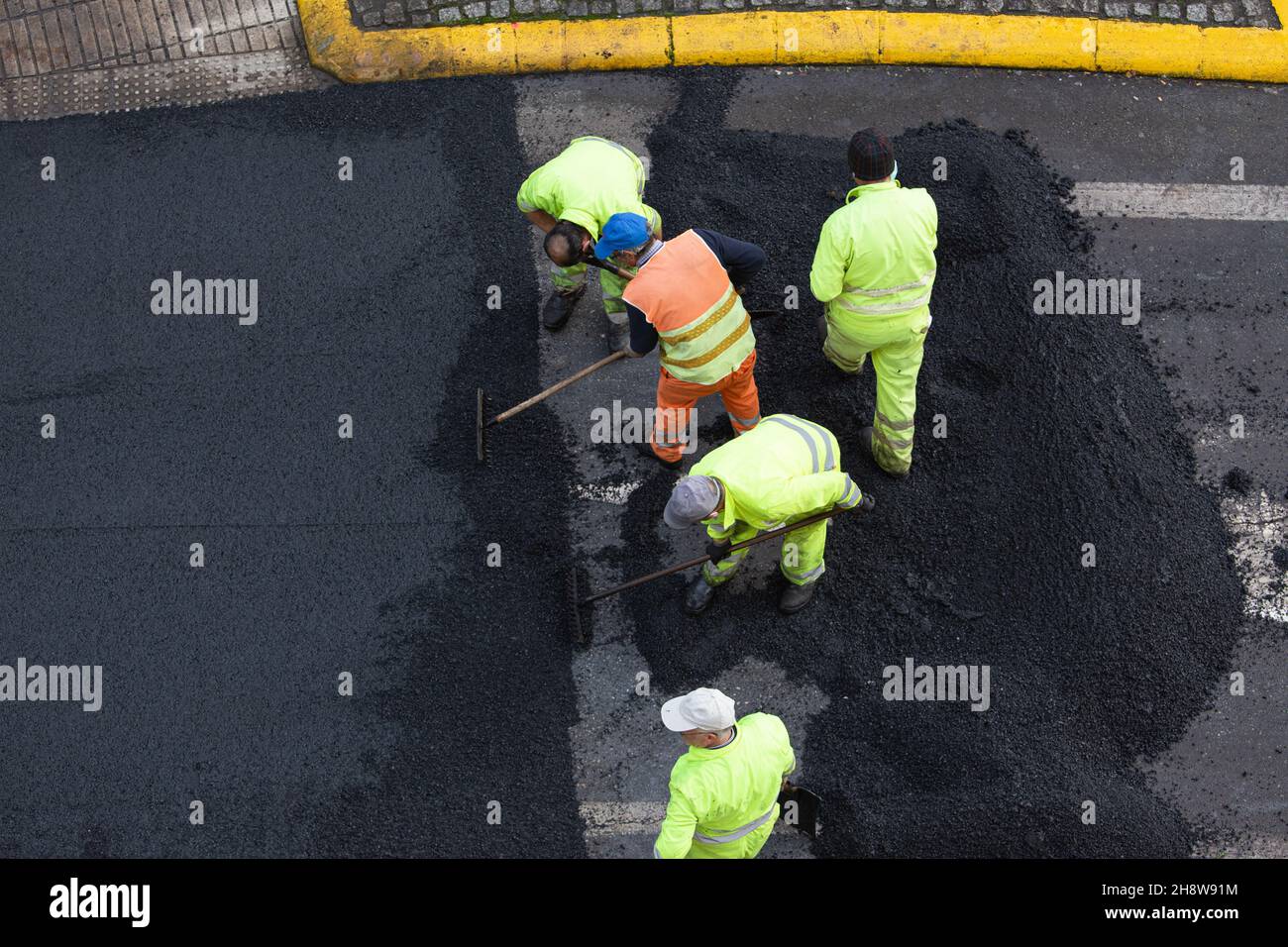 Santiago de Compostela, december 1, 2021: Workers during Asphalting Road Work on city street. Asphalt paving. High angle view Stock Photo