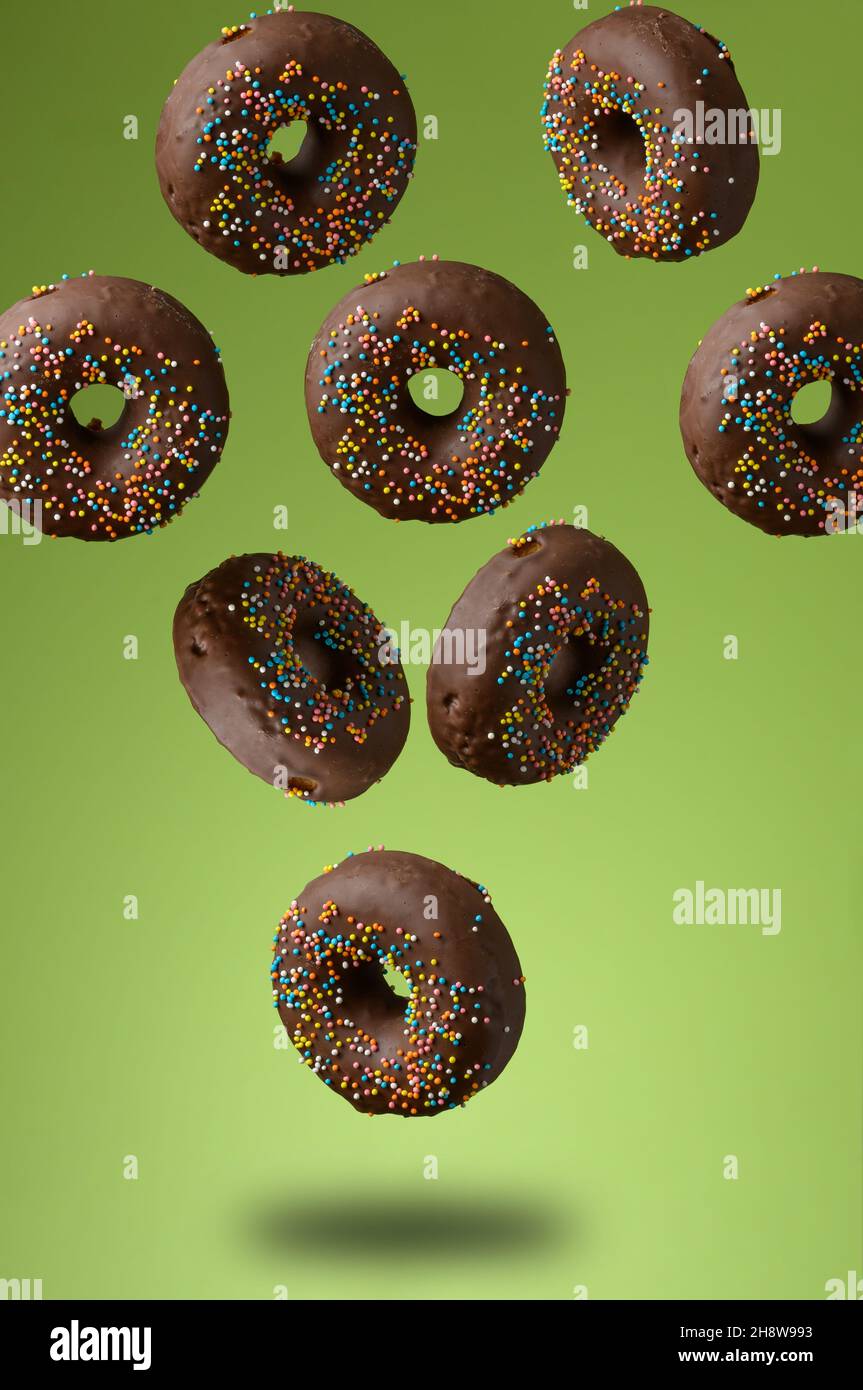 chocolate round donuts with multicolored sugar sprinkles levitate on a ...