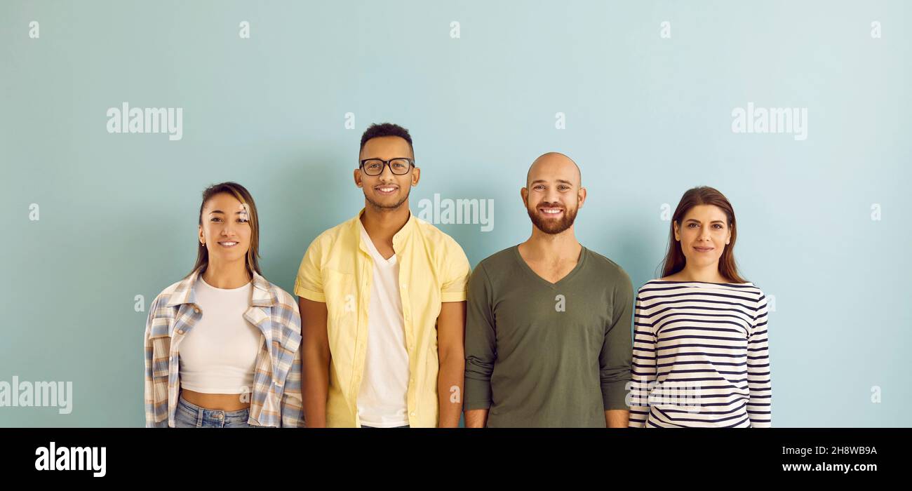 Diverse group of happy young people standing in row against blue studio ...