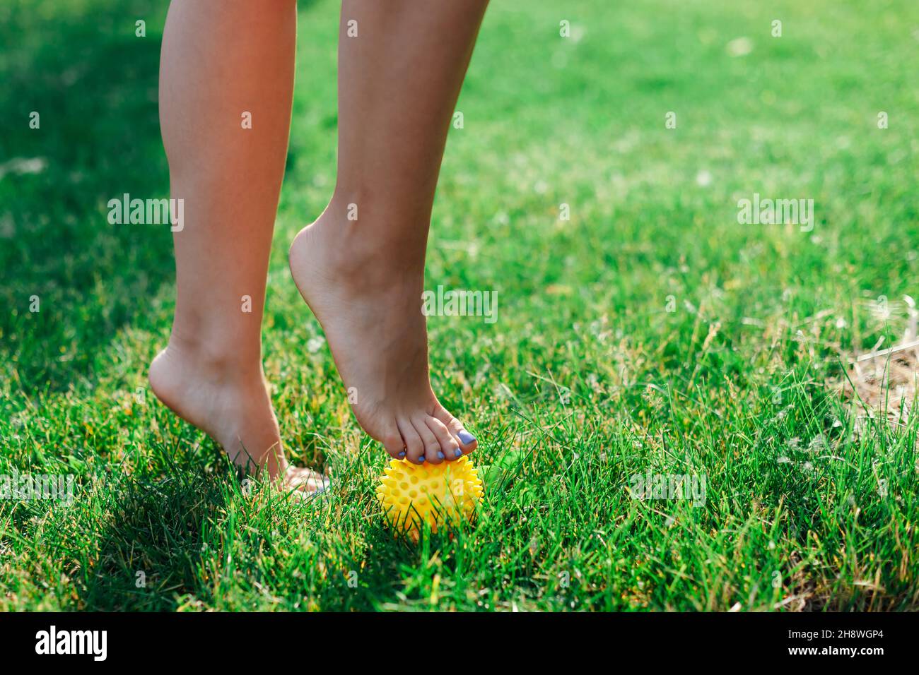 spiky massage rubber for myofascial release and improvement of lymphatic system, woman feet on green grass in forest Stock Photo