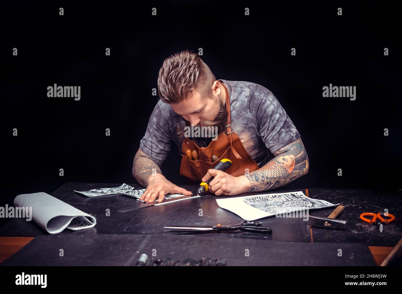 Professional Leather Worker cuts out leather goods Stock Photo