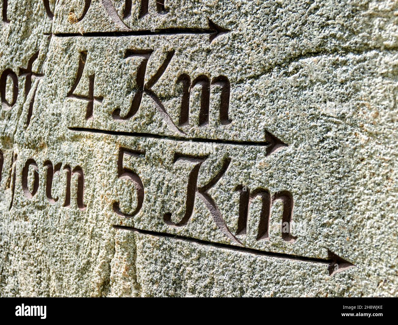 Signpost carved in stone with an arrow and the distances of 4 and 5 kilometers Stock Photo