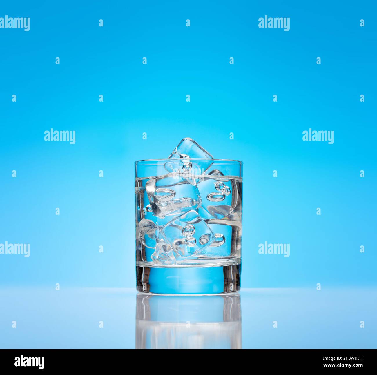 Glass with water and ice cubes over blue background Stock Photo - Alamy