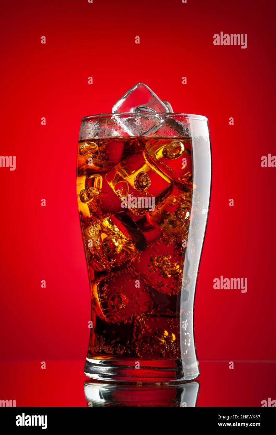 Cola with ice. Fresh cold sweet drink with ice cubes. Over red ...