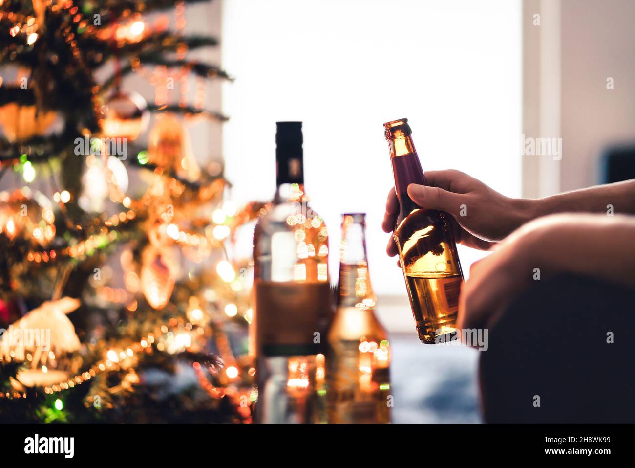 Christmas party with alcohol bottles. New year's celebration. Beer, wine and vodka. Festive Xmas tree. Alcoholism and drinking problem concept. Stock Photo