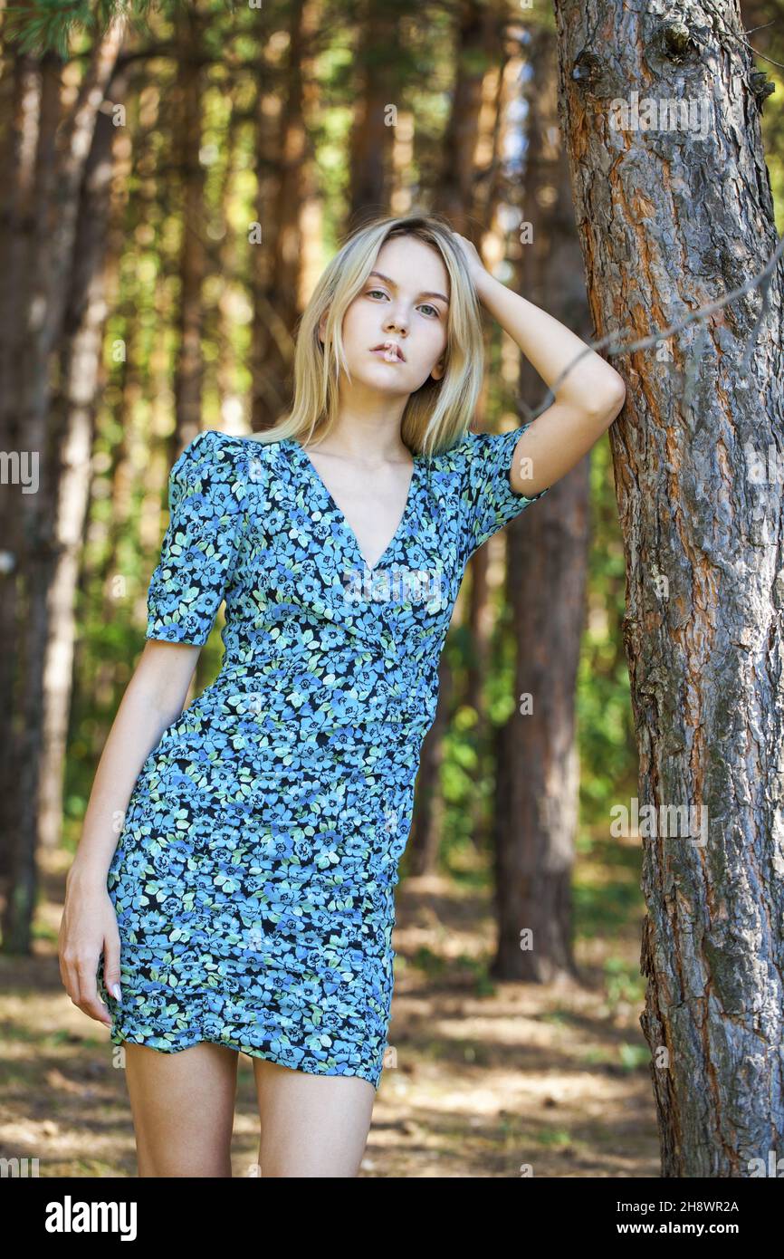 Portrait of a young beautiful blonde girl in blue flowers dress in ...
