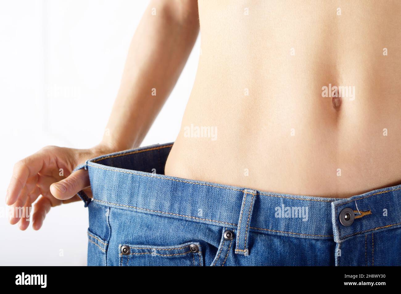 Caucasian female model in blue jeans showing her flat stomach. Weightloss concept. Stock Photo
