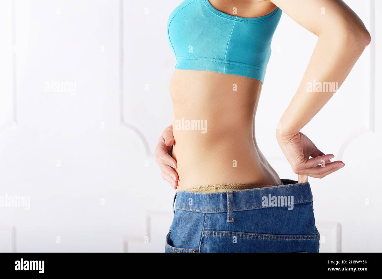 Caucasian female model in blue jeans showing her flat stomach. Weightloss concept. Stock Photo