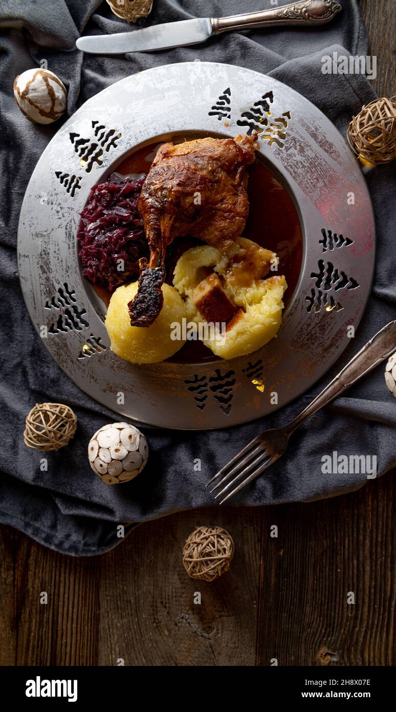 Traditional german christmas meal with roast duck, potato dumplings, brown sauce and red cabbage on a silver plate Stock Photo