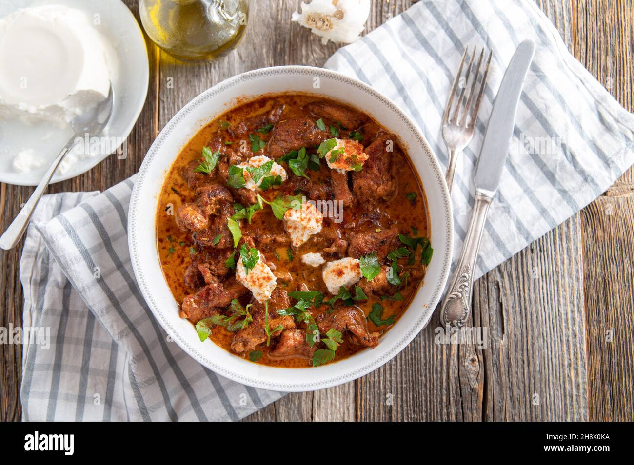 Goulash or ragout in a delicious paprika cream sauce with ricotta topping. Stock Photo