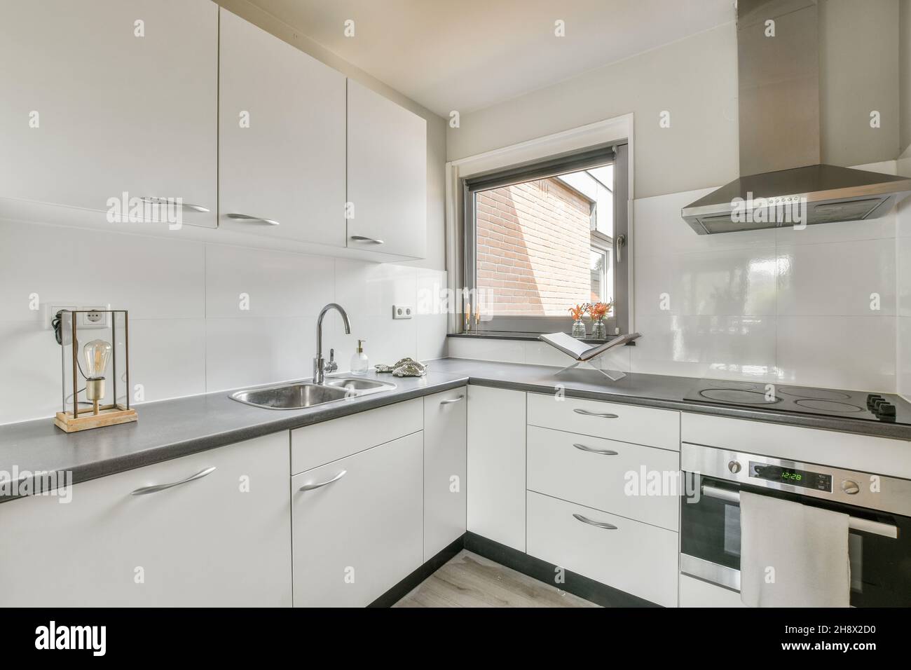 Modern kitchen with white cupboards and built in appliances in flat ...