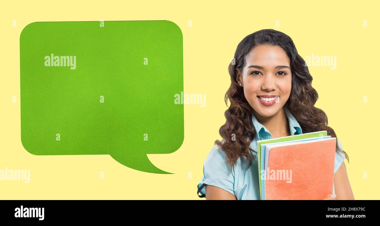 Digital composite of blank green speech bubble with copy space by smiling woman holding books Stock Photo