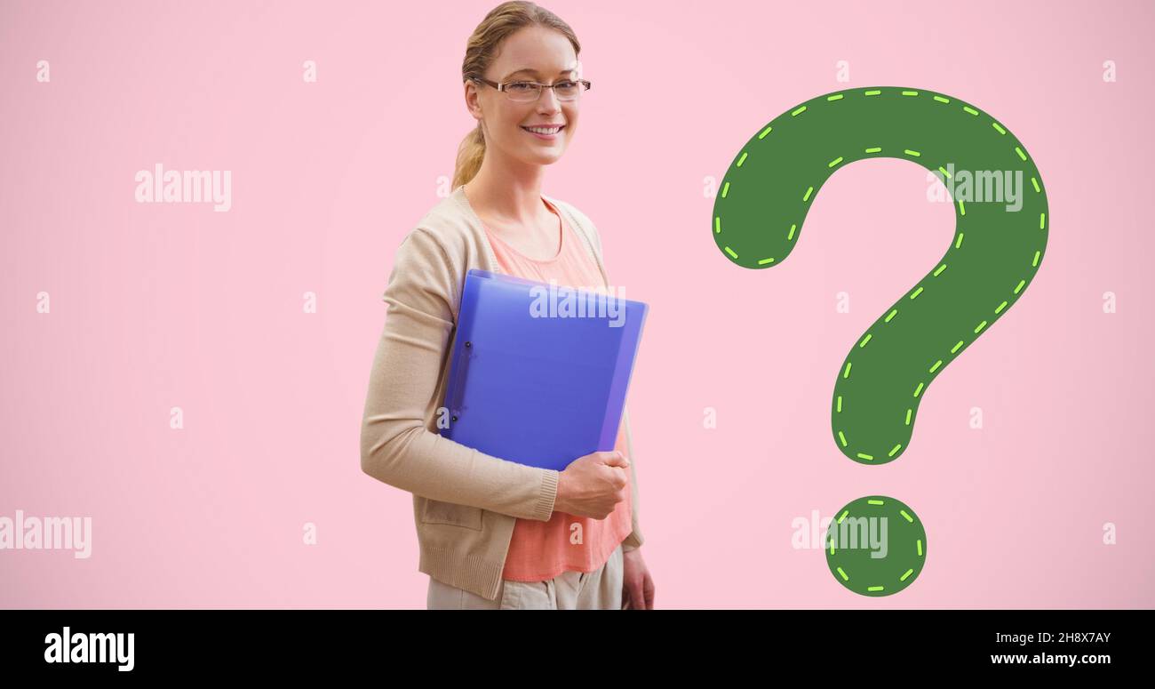 Portrait of smiling young female student holding file by green question mark on pink background Stock Photo