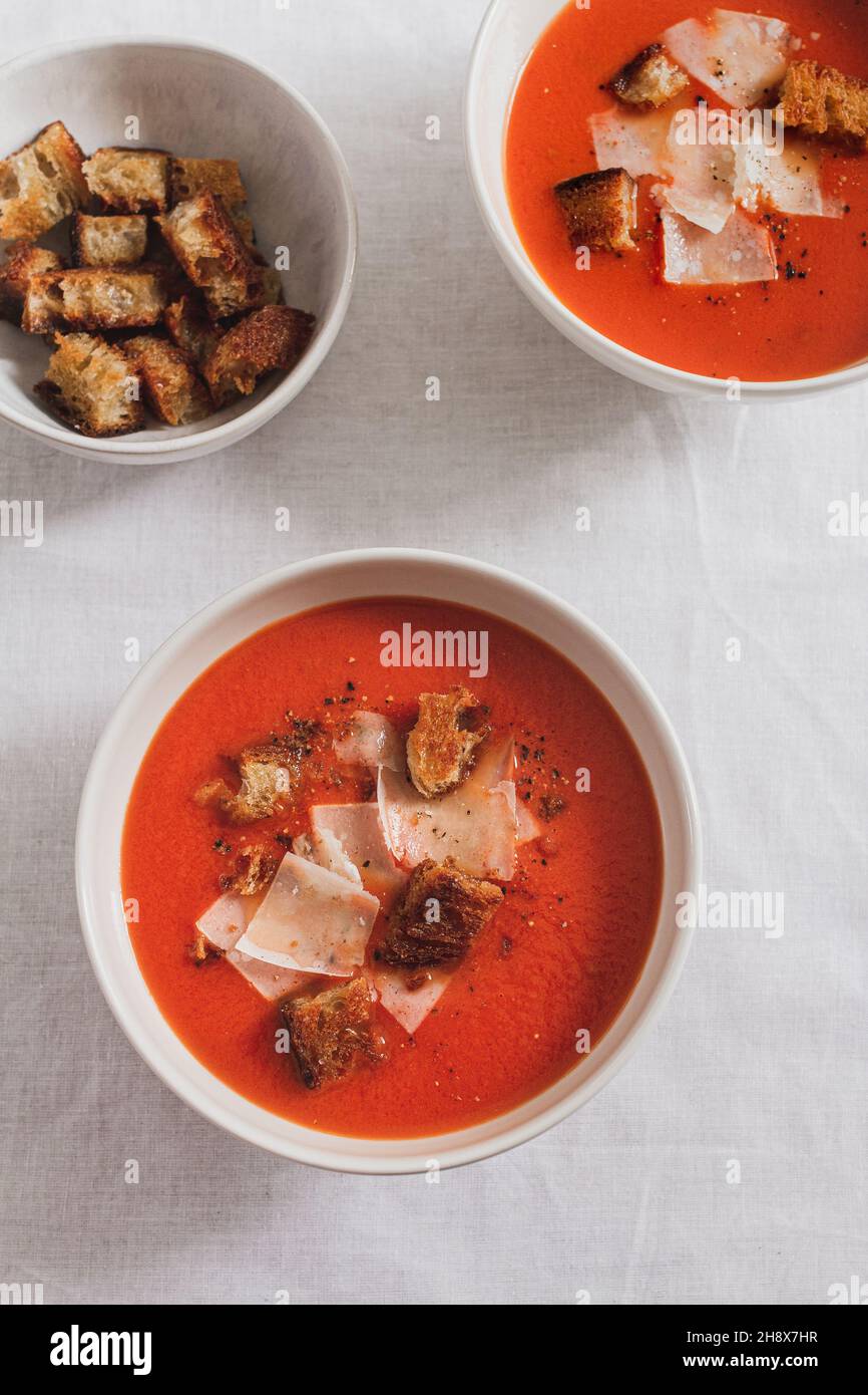 Two bowls of homemade tomato soup topped with croutons and parmesan cheese shavings. Stock Photo