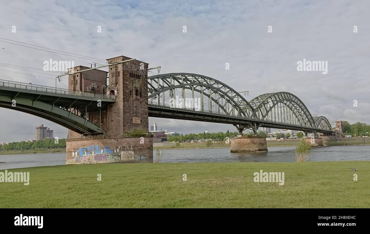 Arched railway bridge over river Rhine in oller Wiesen city park, Cologne, Germany Stock Photo