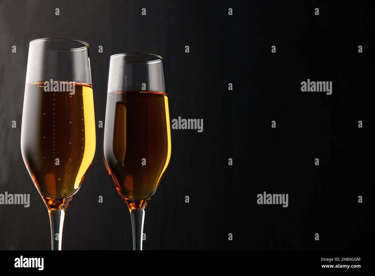 Two glasses of champagne, wine on a black background, a place for text on the right, copyspace. New year and Christmas background Stock Photo