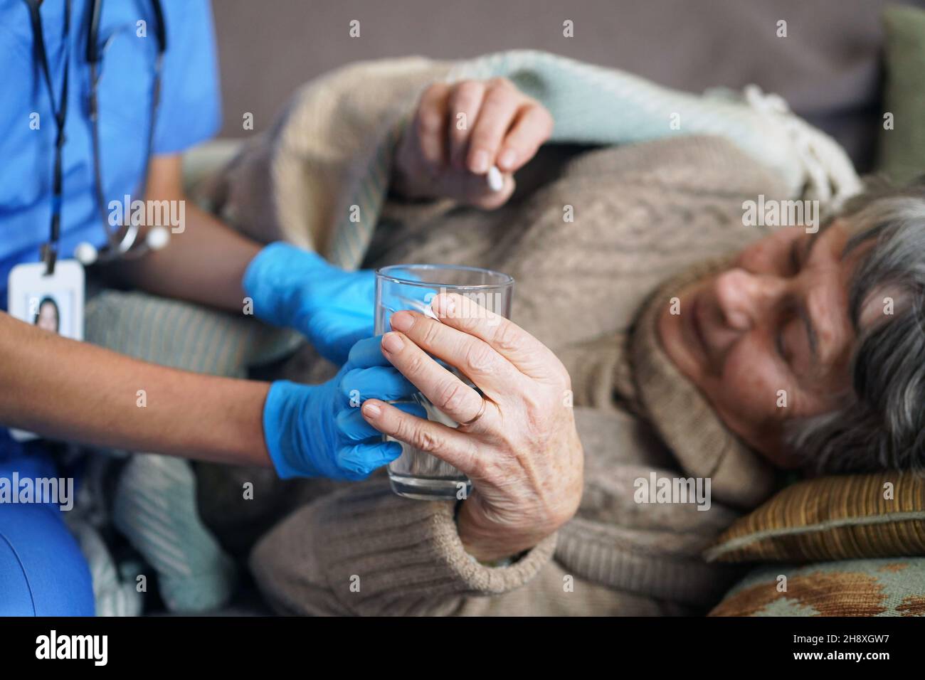 A young nurse is caring for an elderly 80yearold woman at home Stock