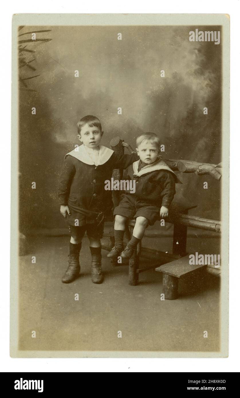 Original Edwardian era studio portrait postcard with props and painted background, of two brothers called Willie and Harry, Illingworth, Yorkshire, England, UK circa 1910 Stock Photo