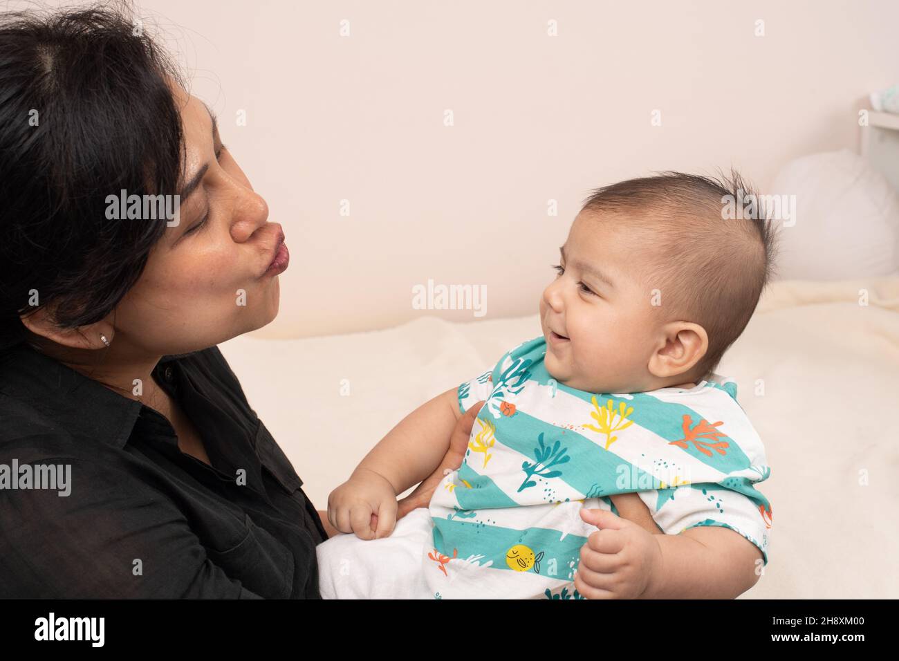 3 month old baby boy interaction with mother smiling as she makes sound with her lips Stock Photo