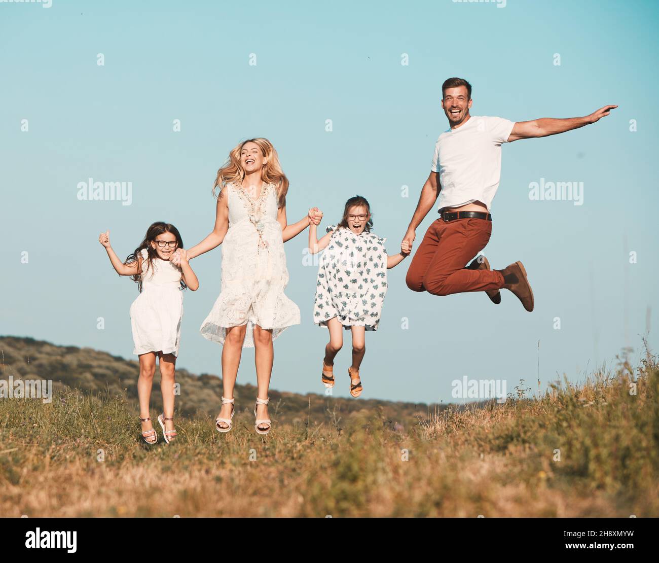 child family outdoor mother woman father girl happy happiness lifestyle having fun bonding jumping Stock Photo