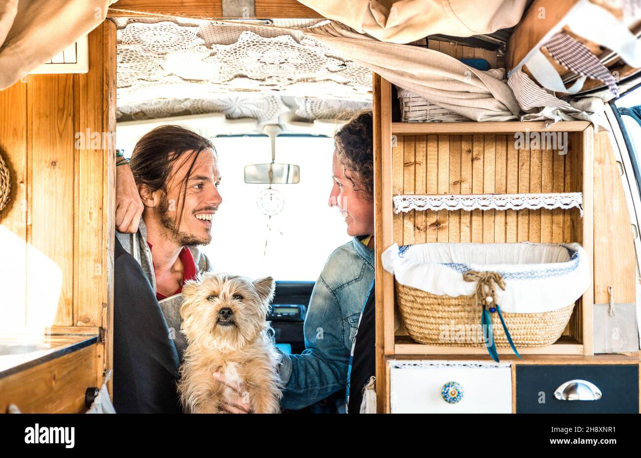 Indie couple with little dog traveling together on oldtimer mini van transport - Travel lifestyle concept with hipster people on minivan adventure Stock Photo