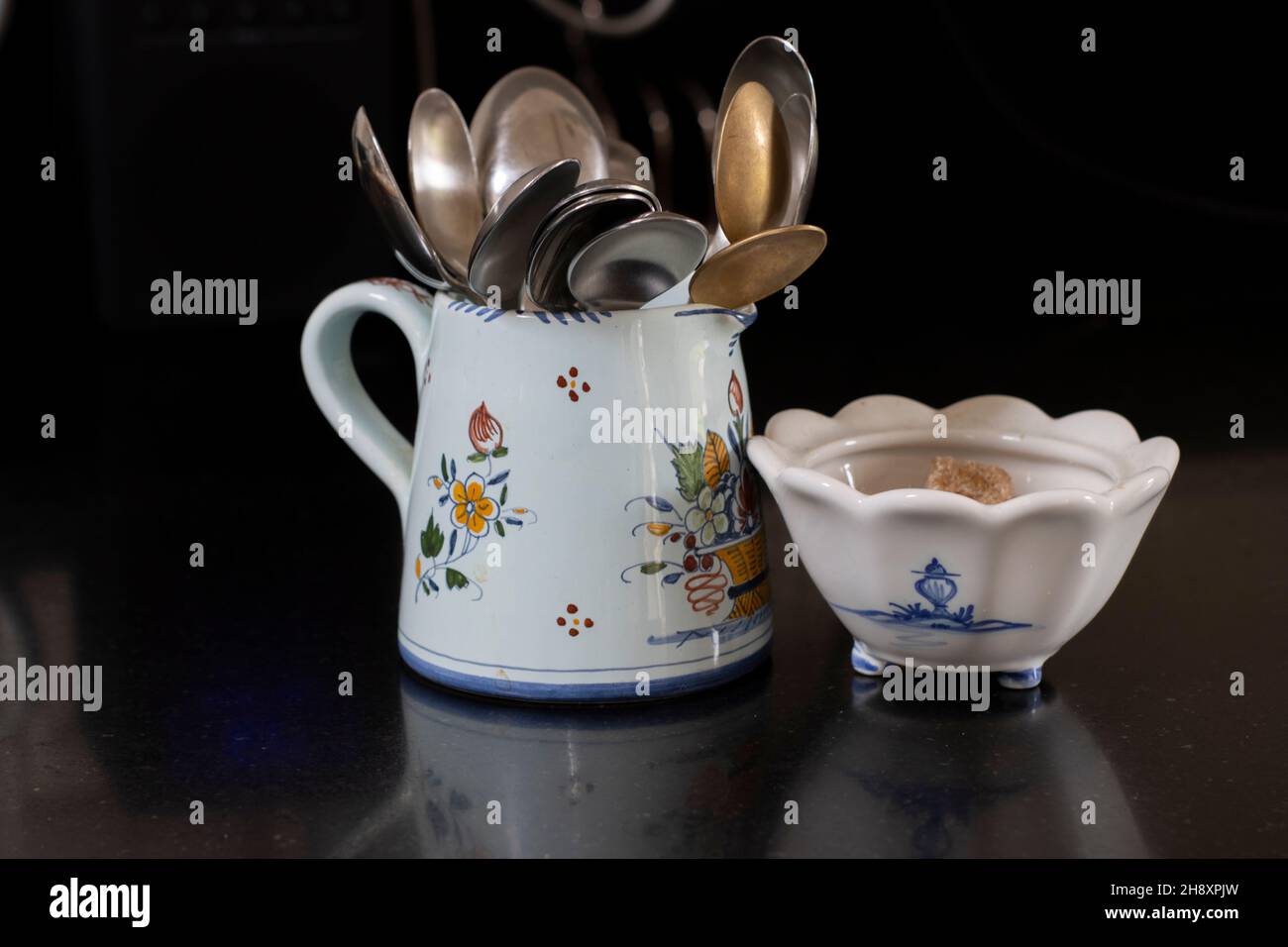 A jug of silver spoons and a bowl of sugar Stock Photo