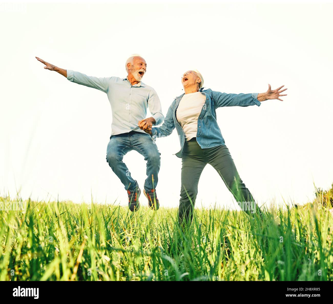 woman man outdoor senior couple happy lifestyle retirement together love jumping fun nature mature Stock Photo