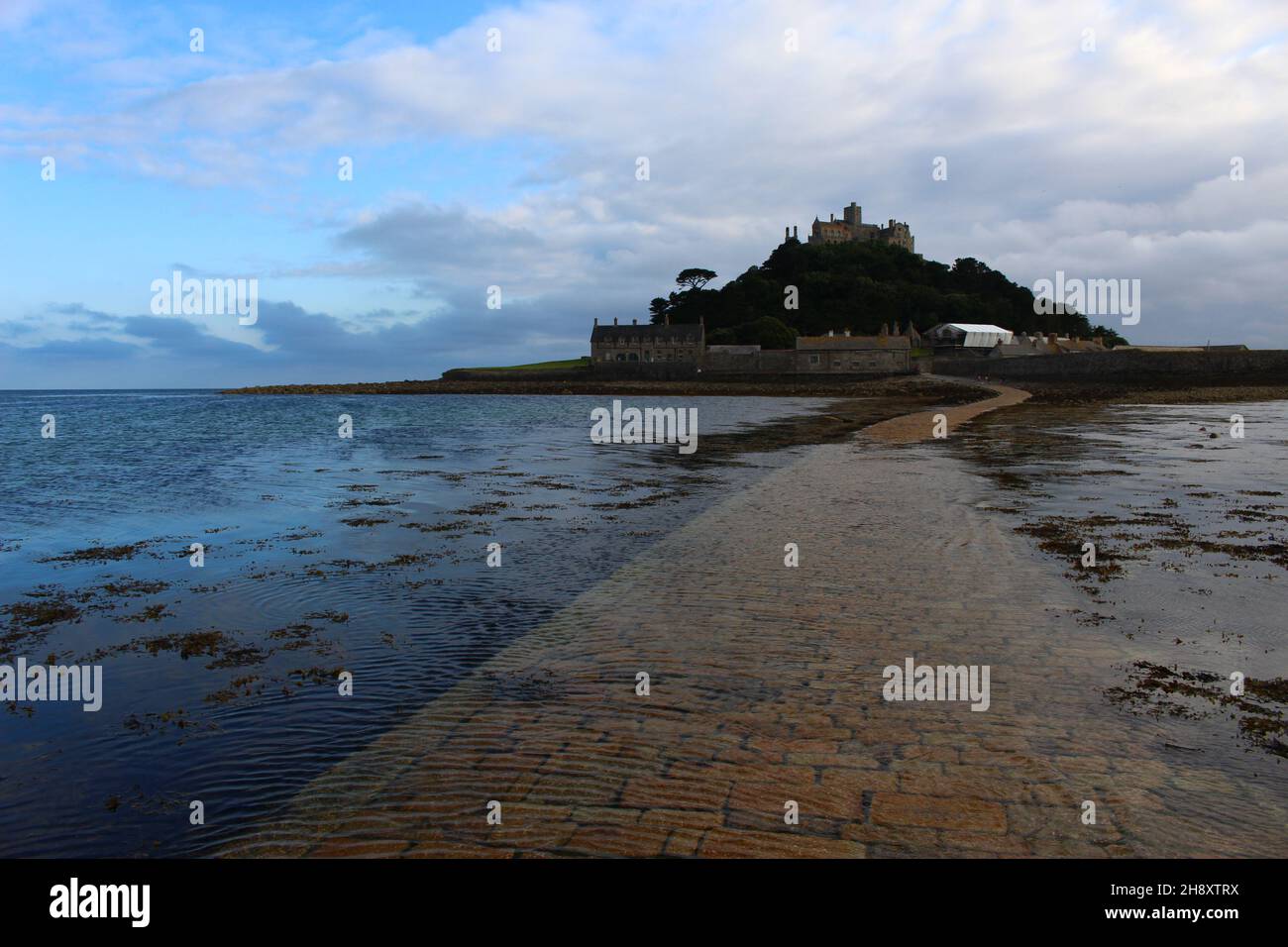 St Michael's Mount, a tidal island in Mount's Bay, and attached man-made causeway partially covered at dusk (Cornwall, United Kingdom). Stock Photo