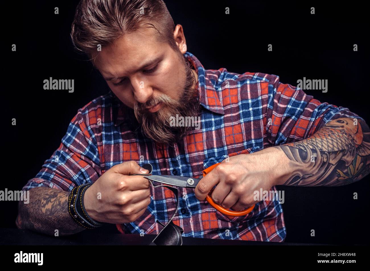Craftsman working with leather performs leather working for a new product at the studio Stock Photo