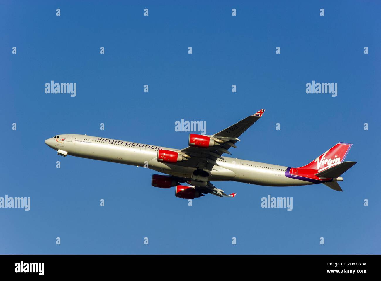 Virgin Atlantic Airbus A340 airliner jet plane G-VFIT climbing after taking off from London Heathrow Airport, UK, into blue sky for long haul flight Stock Photo