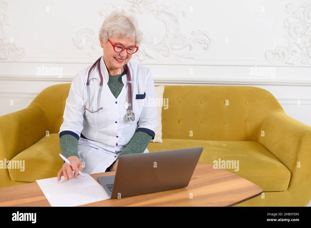 Smiling 60s middle aged female doctor looking at camera. Happy mature elegant old lady posing at hospital  Stock Photo