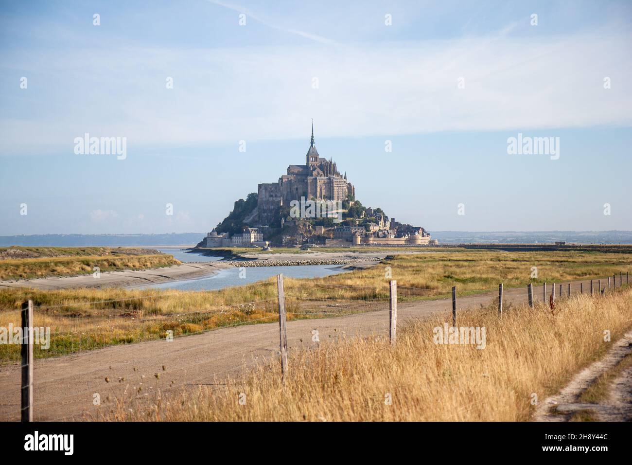 Mont Saint-Michel looking over a footpath and some grassland at the mouth of the Couesnon river, France Stock Photo
