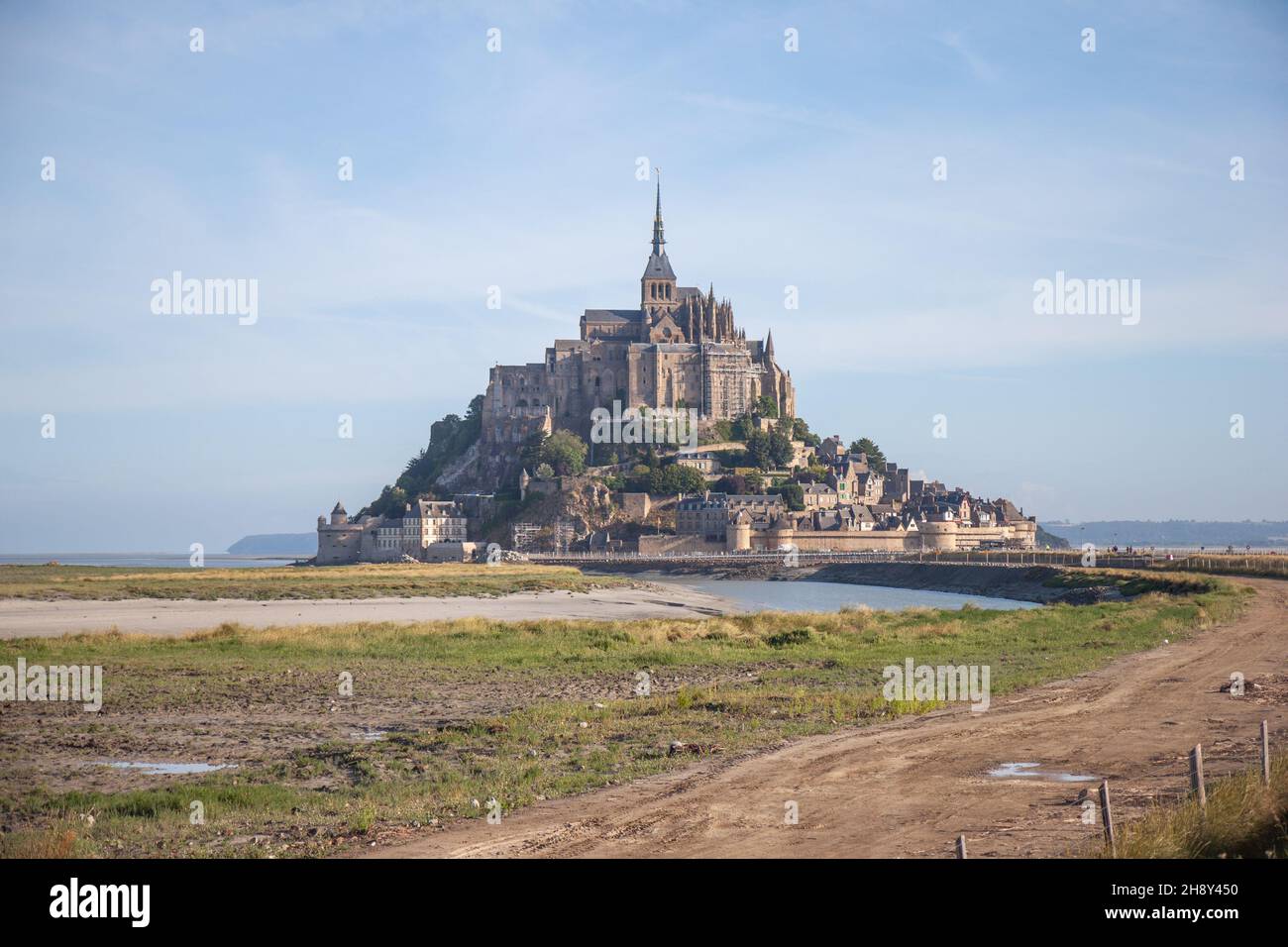 Mont Saint-Michel looking over a footpath and some grassland at the mouth of the Couesnon river, France Stock Photo