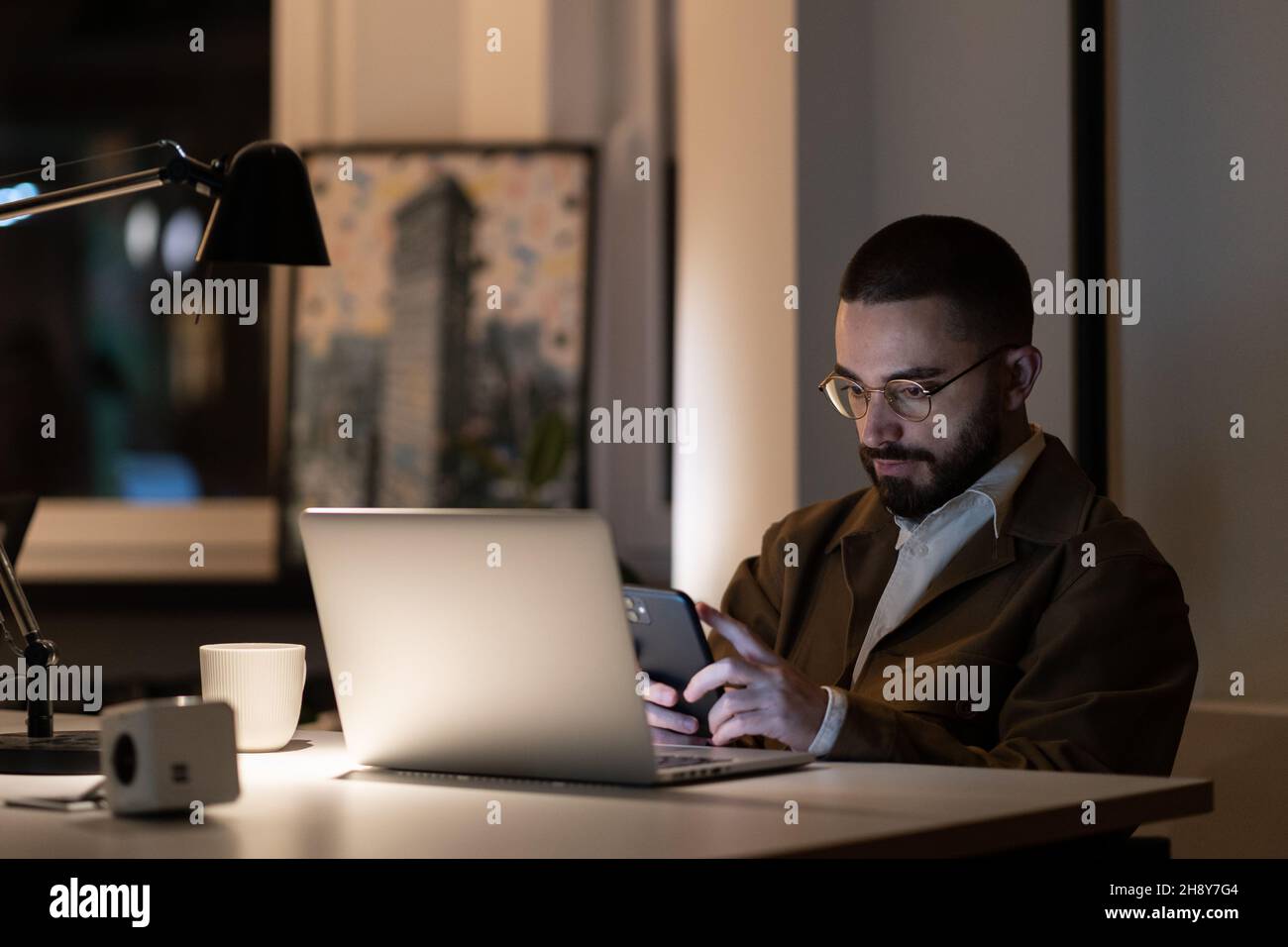 Casual web designer or programmer guy working alone in office late at night before project launch Stock Photo