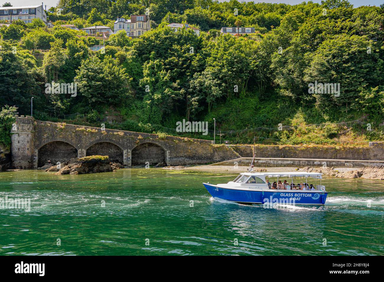 A glass bottom boat takes tourists toward the sea along the East Looe