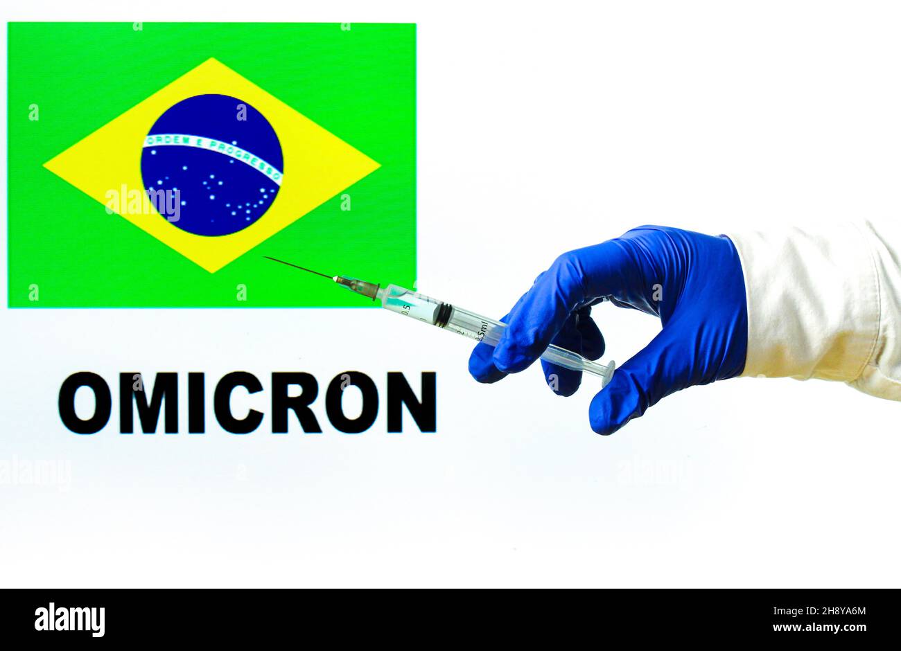 Hand holding syringe with covid vaccine. Brazilian flag and Omicron covid variant word written in the background Stock Photo