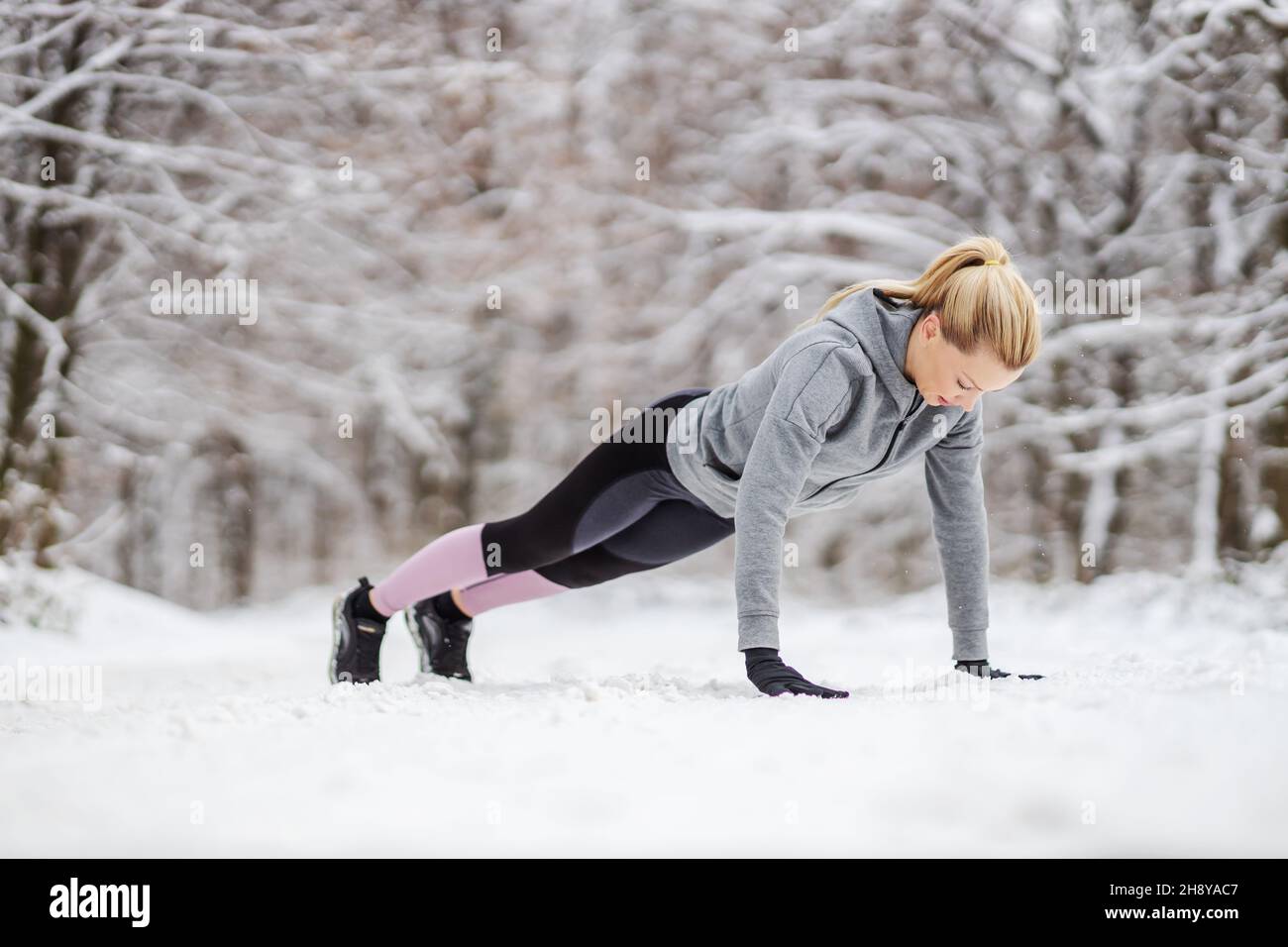 Sportswoman doing push ups on snowy path in nature at winter. Winter fitness, snowy weather, healthy life Stock Photo