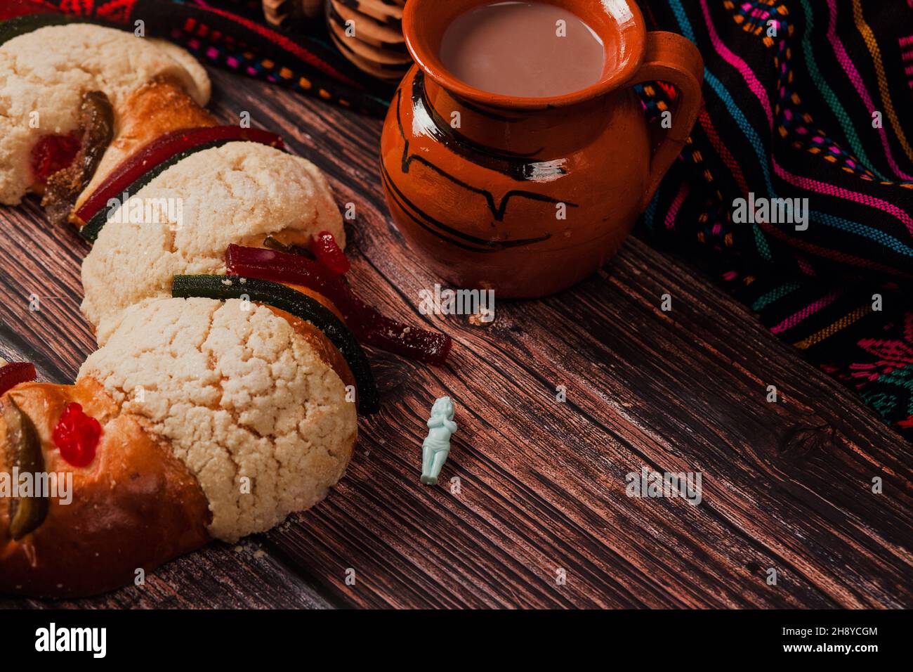 Rosca de reyes or Epiphany cake and clay mug of mexican hot chocolate on wooden table in Mexico Latin America Stock Photo
